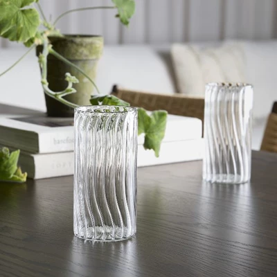 2 genomskinliga dricksglas på ett matbord av mörkt trä