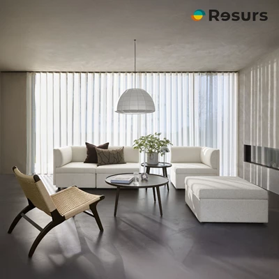 Ljust vardagsrum med modulsoffa, fåtölj, soffbord och lampa.