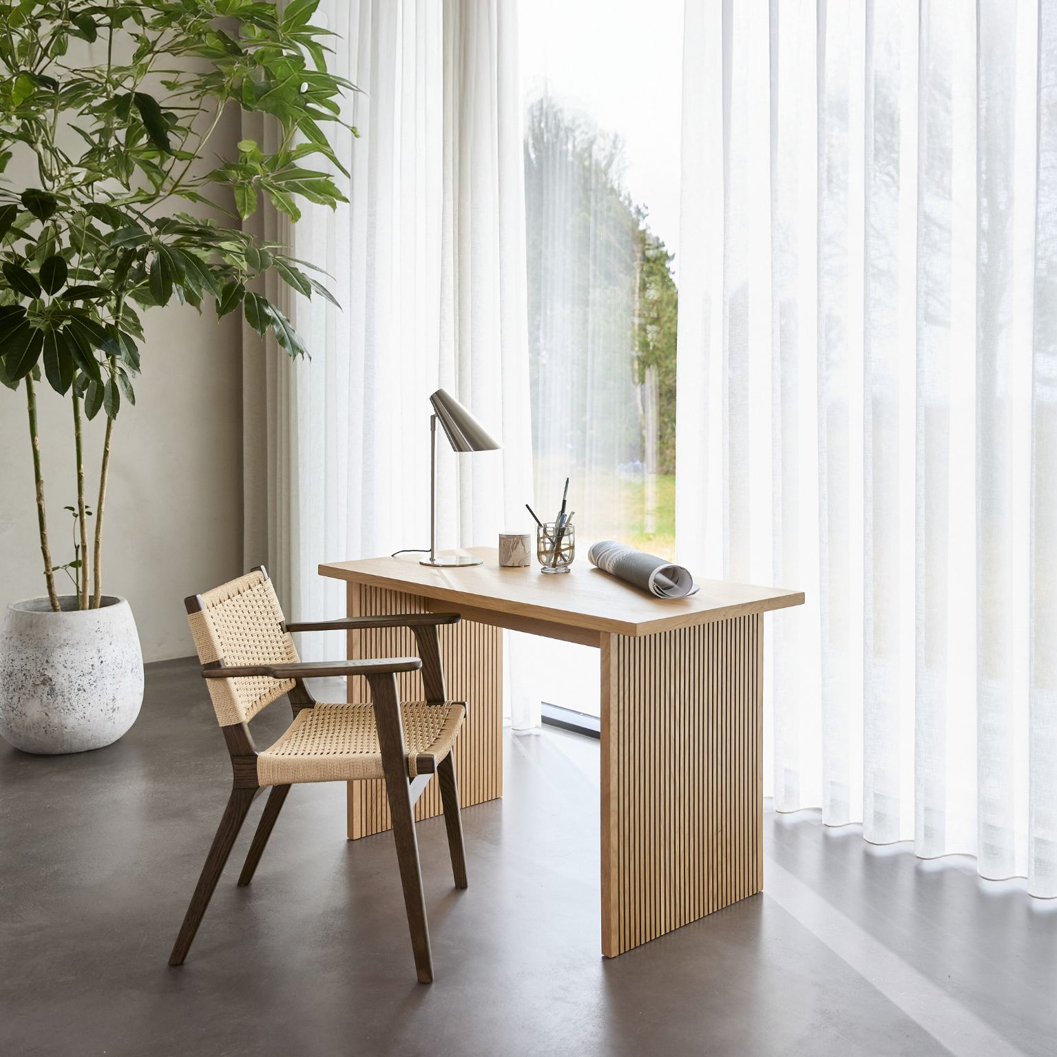 Ljust skrivbord med stol i trä och flätad sits.