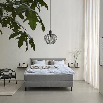 Lys grå dobbeltseng i lyst soveværelse med sort loftlampe