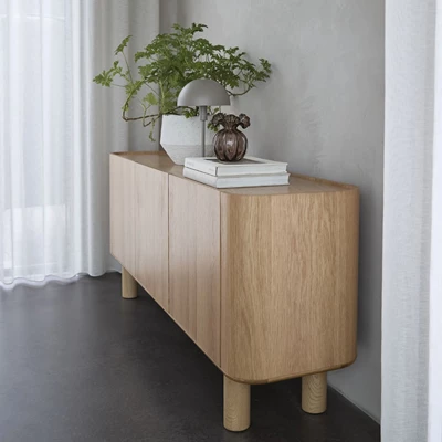 Ljus träsideboard stående på grått betongolv.