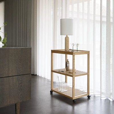 Serveringsvagn i trä med lampa, glas och andra tillbehör.