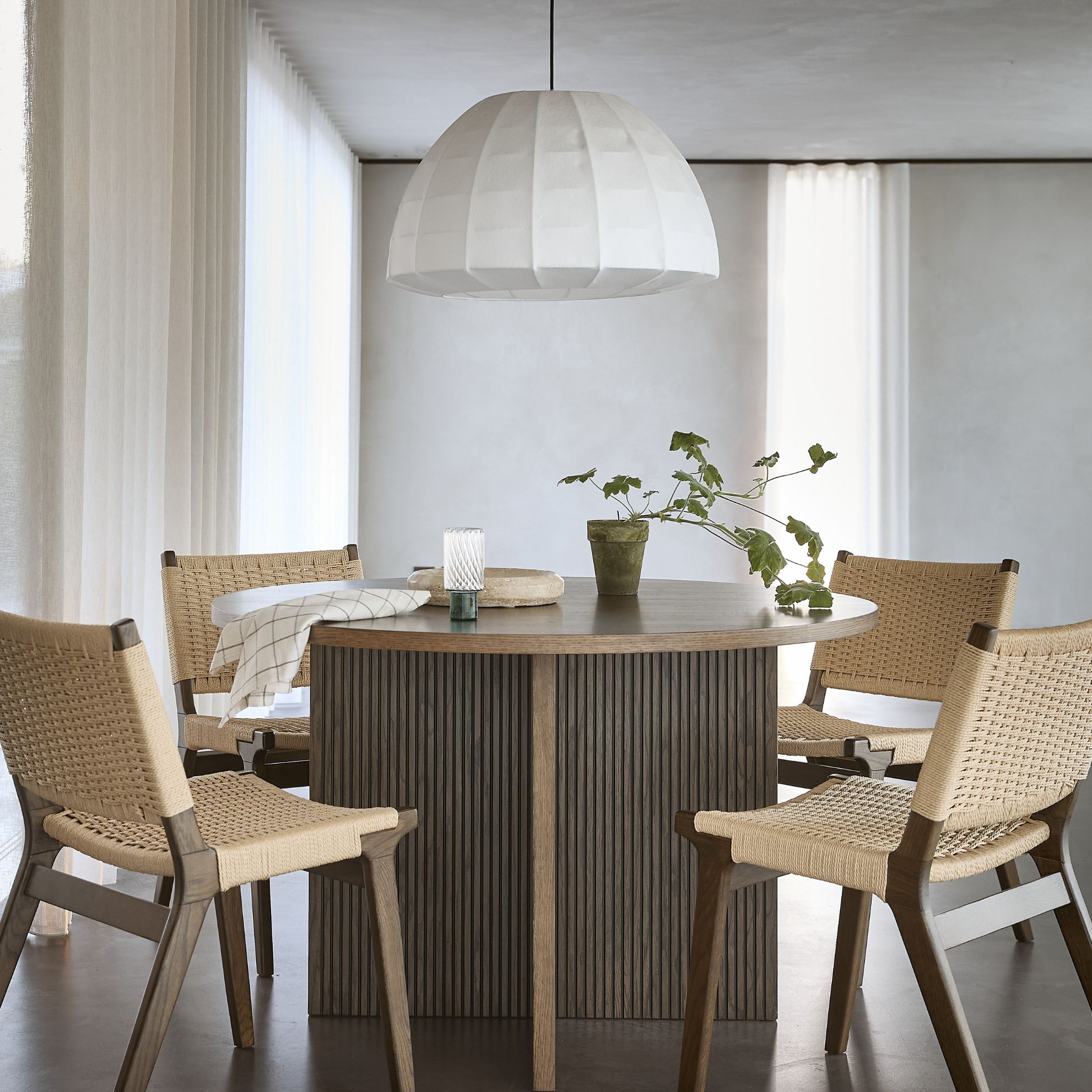 Vardagsrum i nordisk stil med matbord i mörkt trä och vit pendellampa.