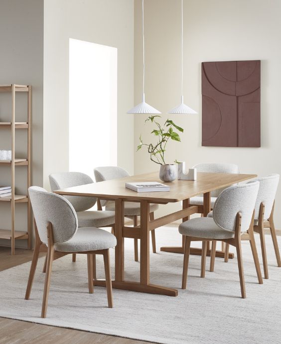 Ljus matsal med träbord, stoppade stolar och tavla på väggen