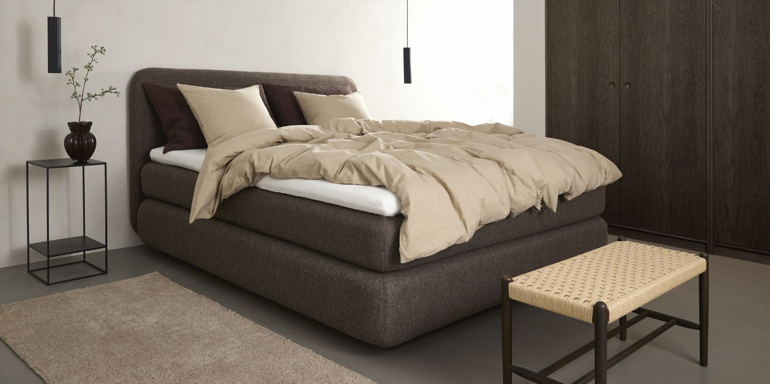 Sovrum i mörka färger med kontinentalsäng i centrum.