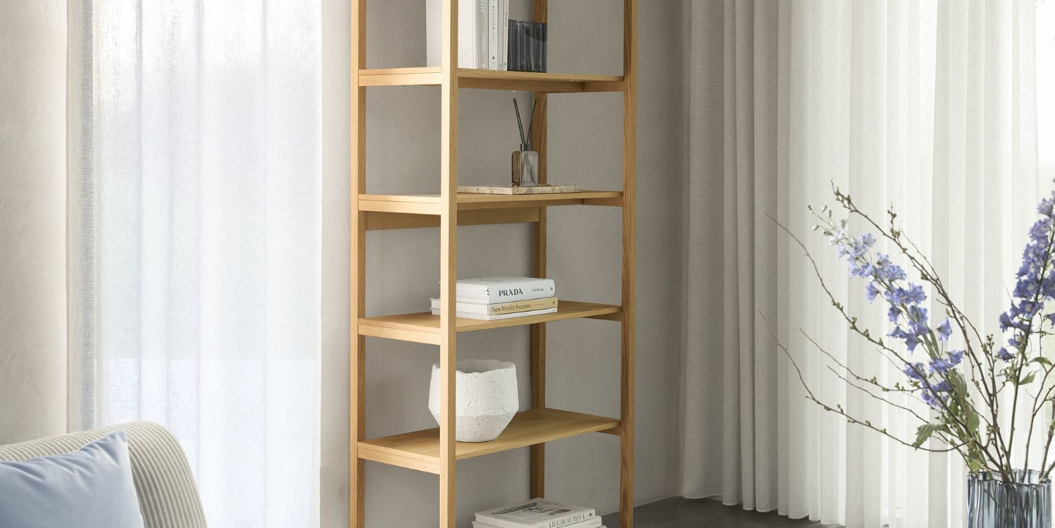 Høj reol i træ med åbne hylder og diverse boligtilbehør