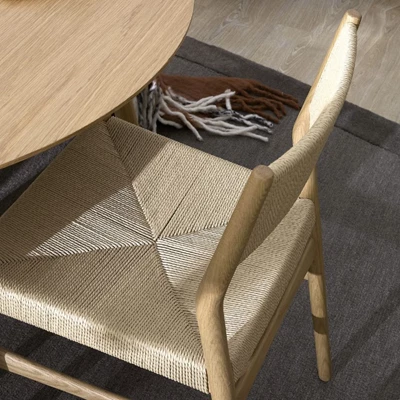 Närbild av matbordsstol med ben i ek och sits och rygg i flätad design.
