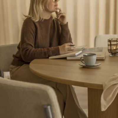 Kvinna sittande vid ett matbord i trä