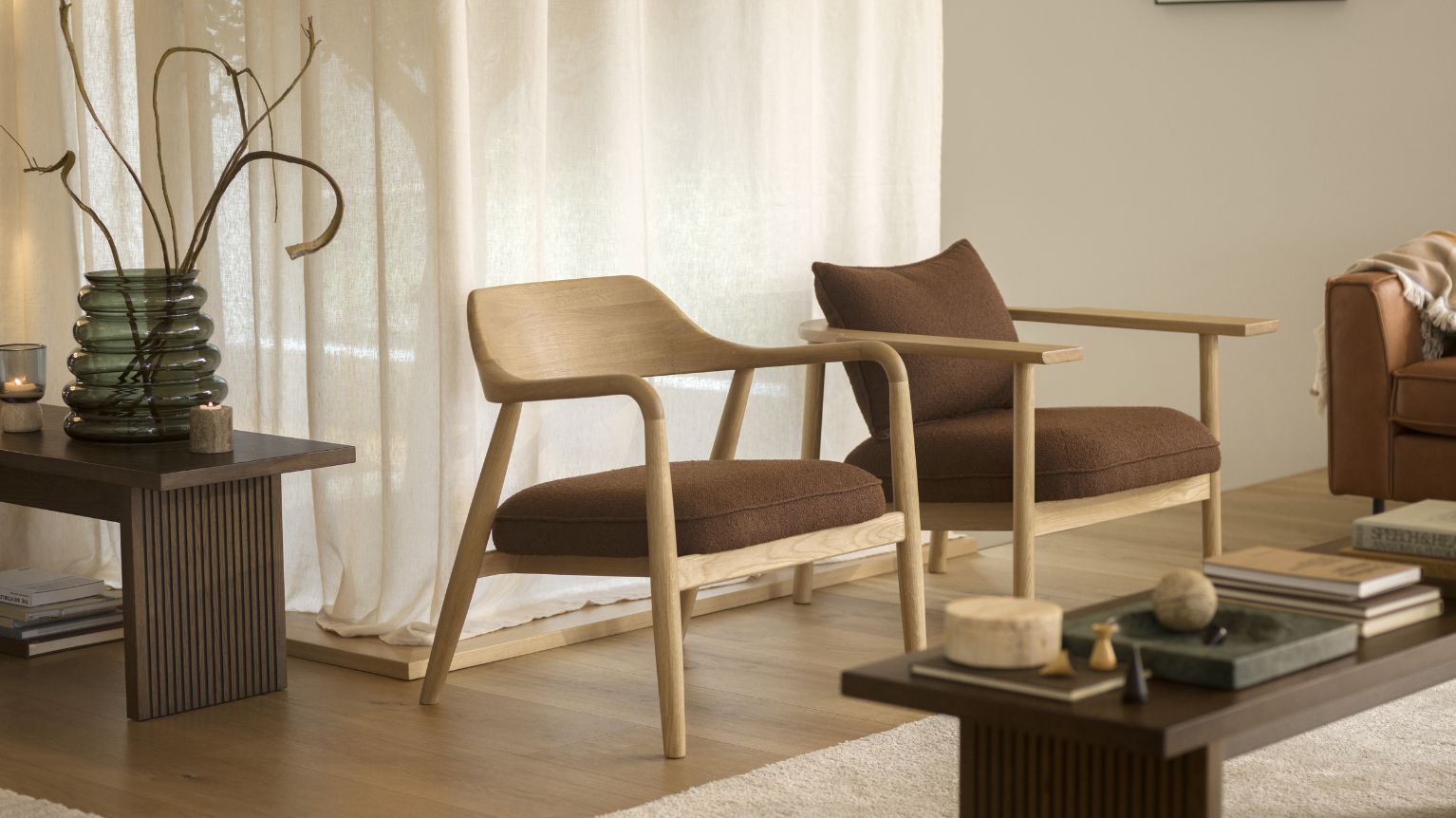 Två fåtöljer i trä med stoppade, röda sitsar. Båda står i ett vardagsrum med trägolv.