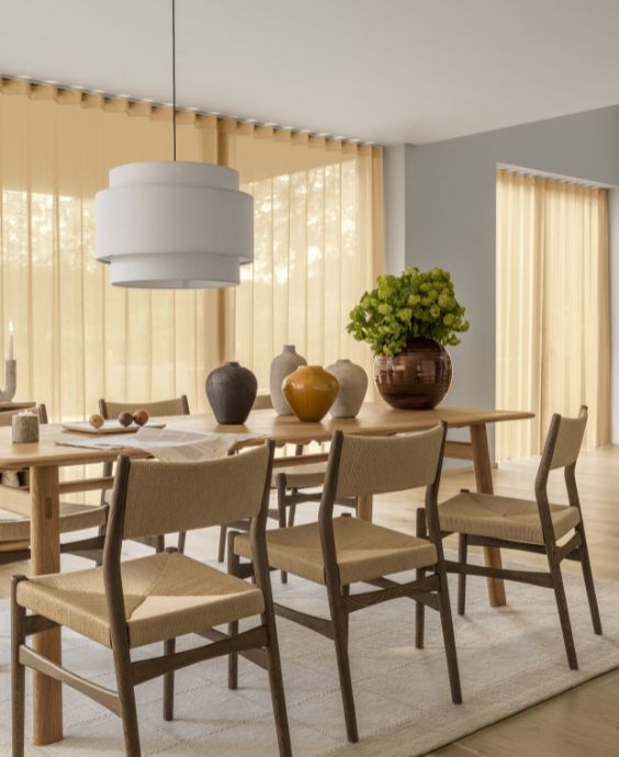 Matsal med matbord i trä samt stolar med mörkt trästativ och sitsar och ryggar i flätning.