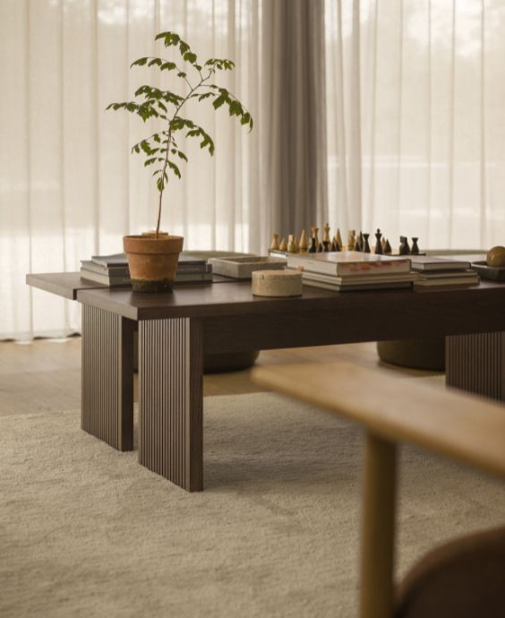 Två soffbord i mörkt trä stående bredvid varandra. Ovanpå står bland annat ett schackspel.