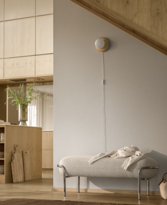 Vit stoppad bänk med kromstativ stående framför vägg.