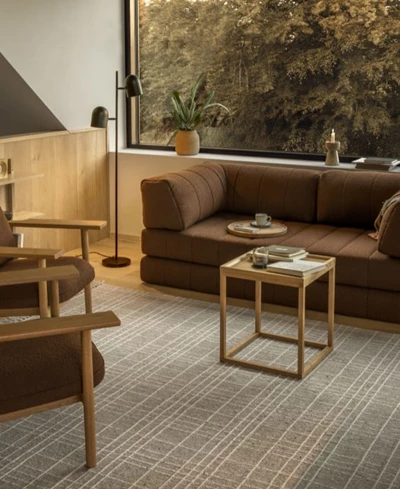 Inblick i mysigt vardagsrum med mörkröd bäddsoffa, soffbord i trä samt fåtöljer med trästomme och mörkröda sitsar.