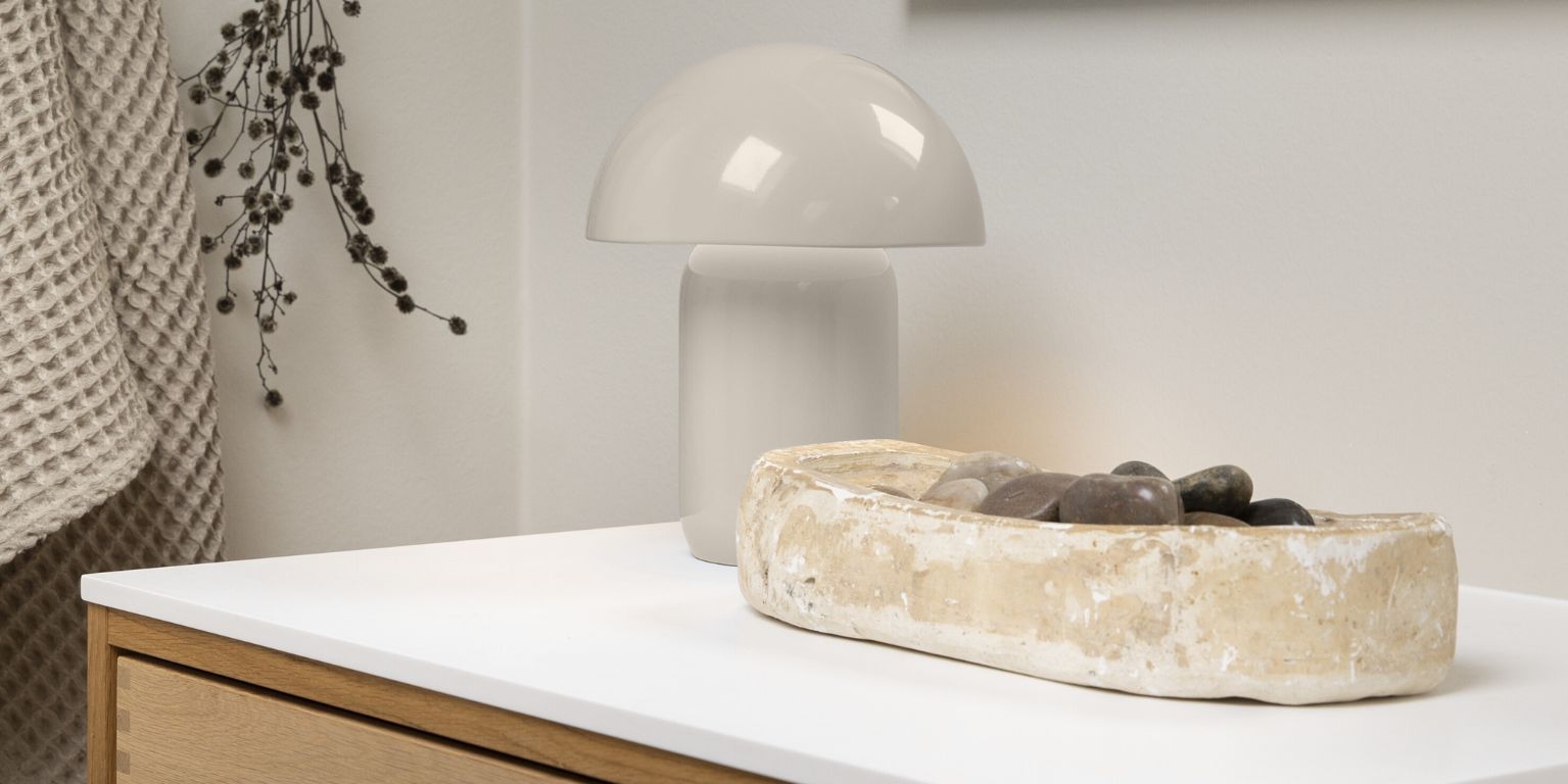 Rustikt, ljust fat tillsammans med ljus bordslampa i badrum.