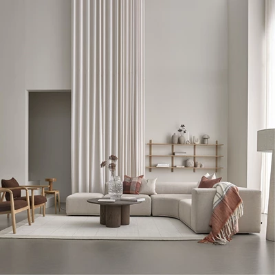 Ljus modulsoffa i vardagsrum med soffbord, matta, vägghylla och diverse mysiga saker