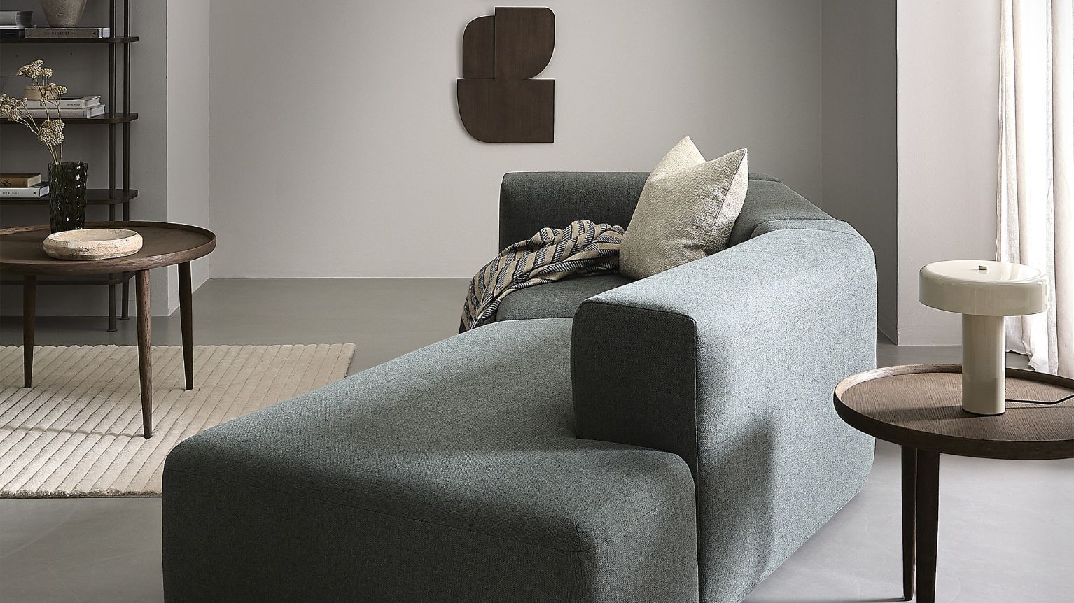 Sofa i grøn set fra siden stående i stue med bl.a. sofabord og pynt på væggen