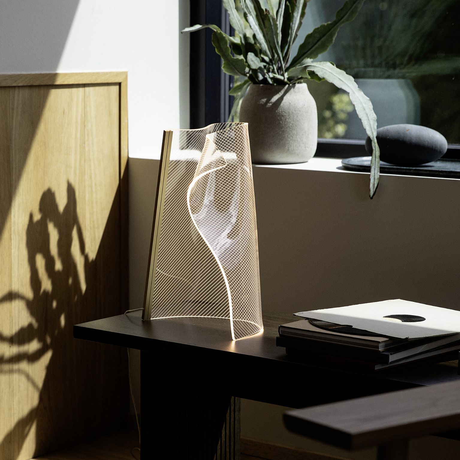 Organiskt formad LED-bordslampa stående på mörk yta