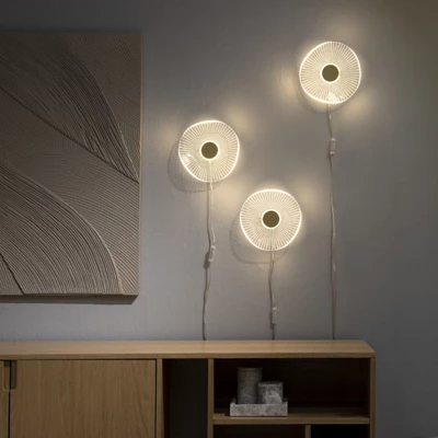 3 LED-vägglampor i akryl hängande på vägg ovanför träskänk.