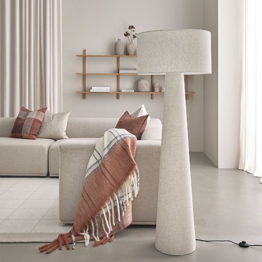 Golvlampa i ljust textil stående på betongolv