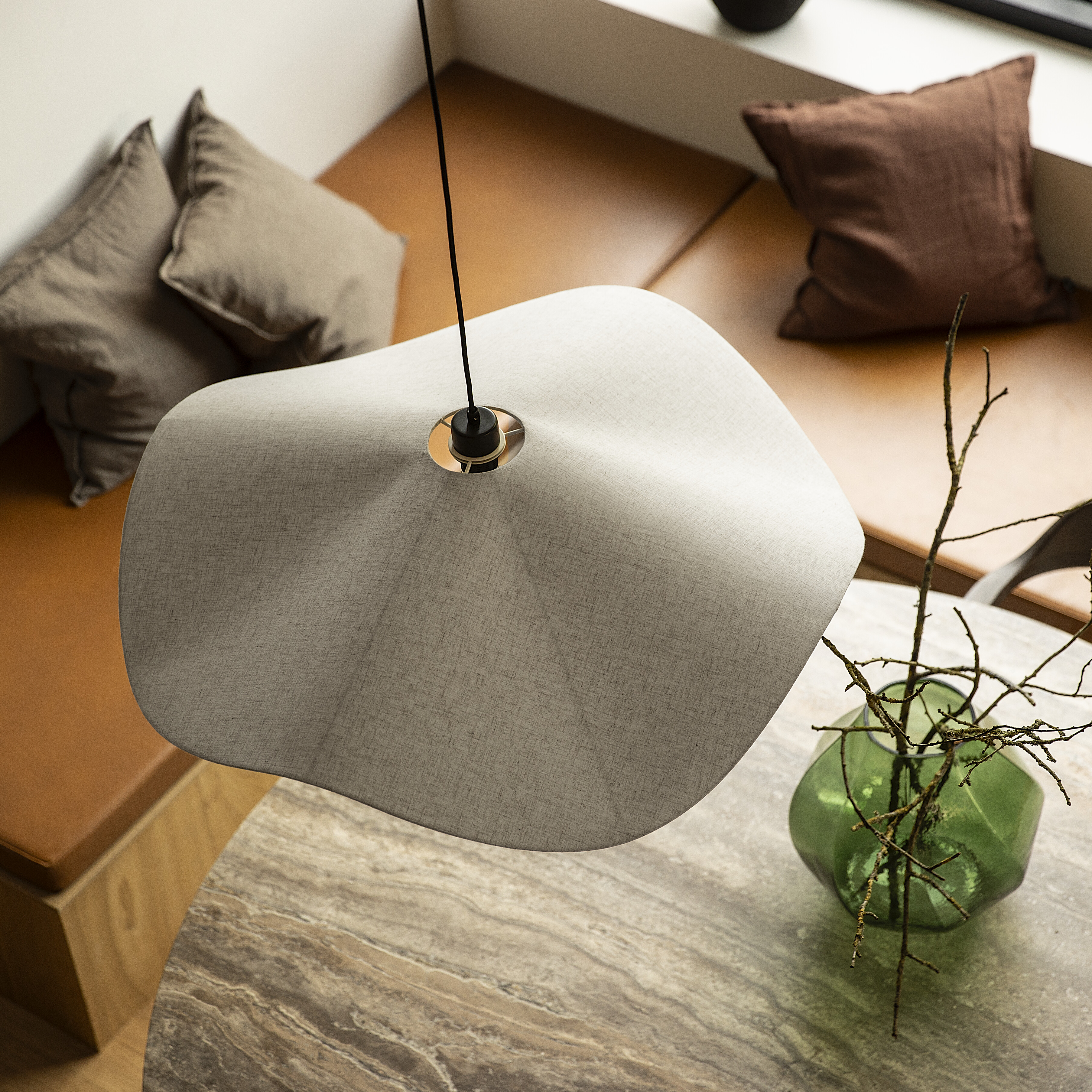 Ljus, organiskt formad pendel i vitt tyg hängande över matbord.