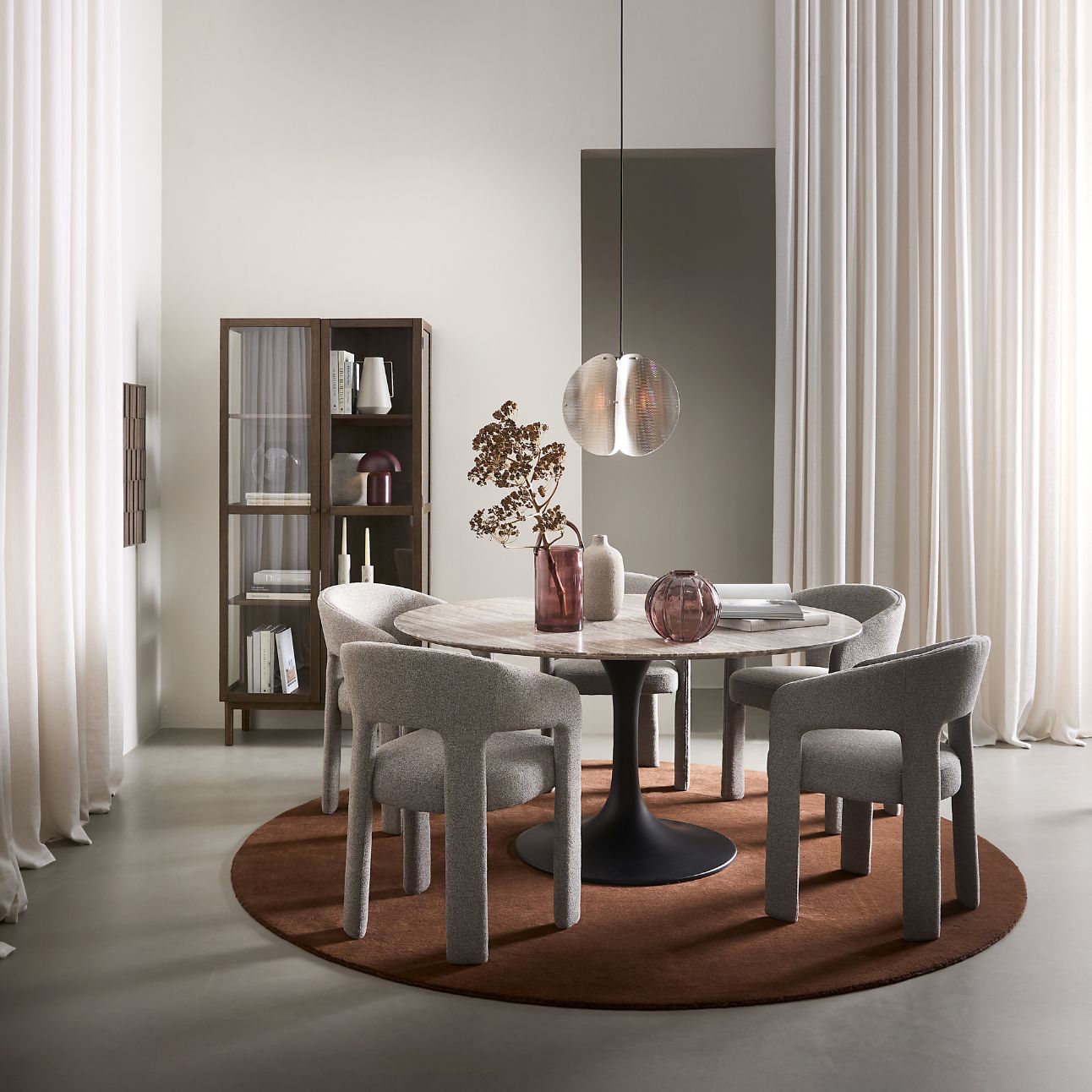 Matrumsmiljö med grå stolar, runt matbord och en röd, rund matta