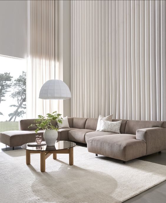 U-formad soffa i sandfärgat tyg på vit matta i minimalistiskt vardagsrum