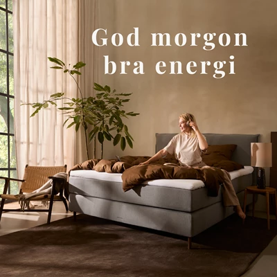 Kvinna som sitter på en säng i ett stämningsfullt sovrum