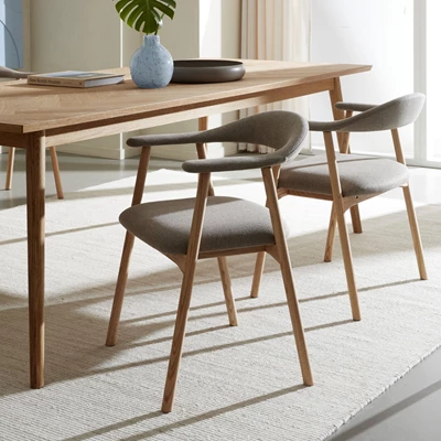 To gråpolstrede spisebordsstole ved spisebord i træ