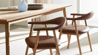 Matstolar i brunt läder vid ett matbord i trä