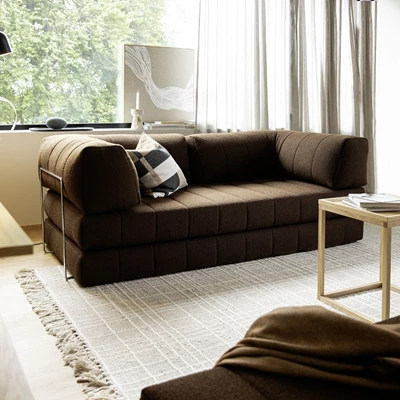 Brun bäddsoffa placerad framför fönster