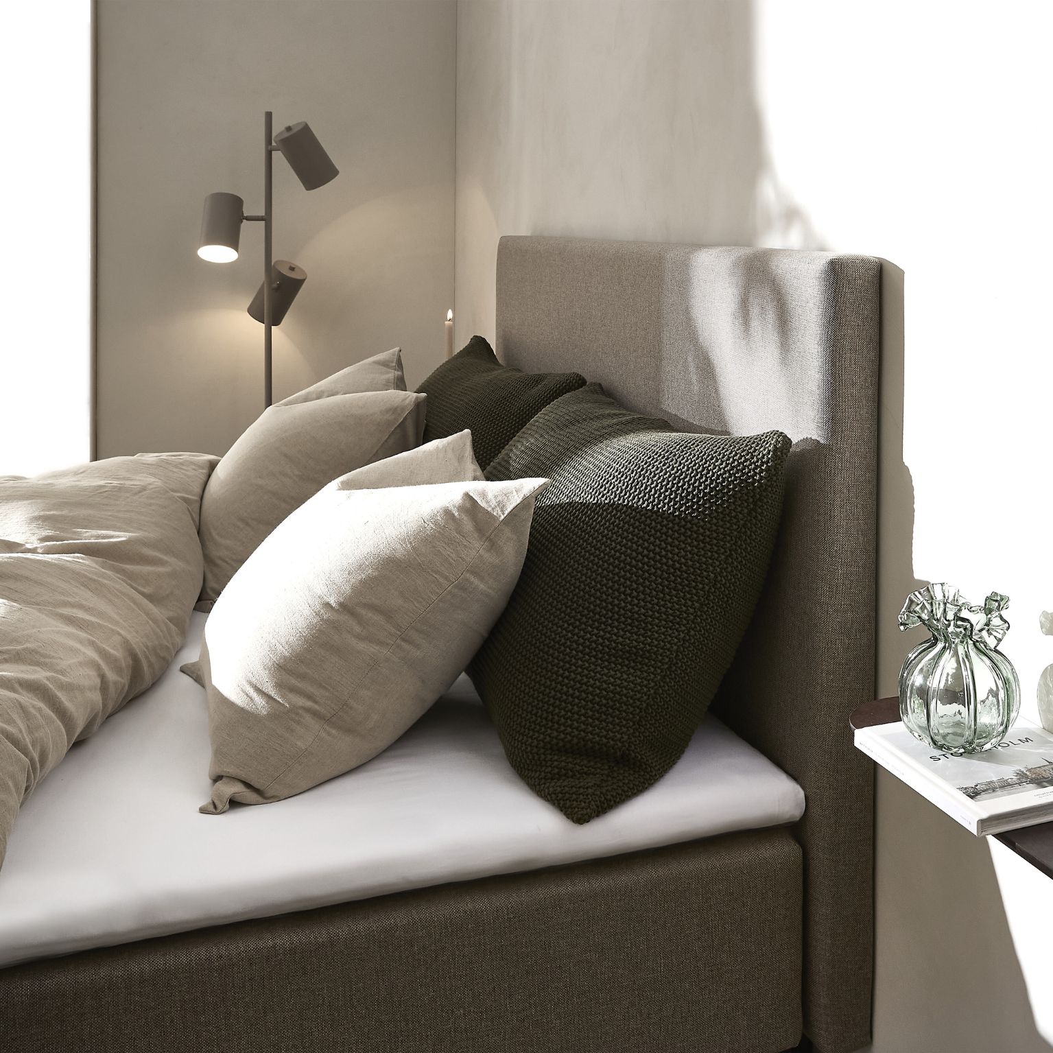 Grå sänggavel på säng med täcken och kuddar.