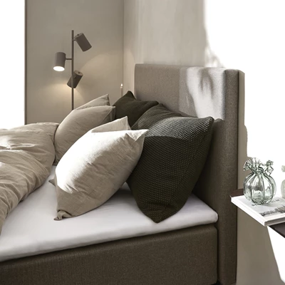 Grå sänggavel på säng med täcken och kuddar.