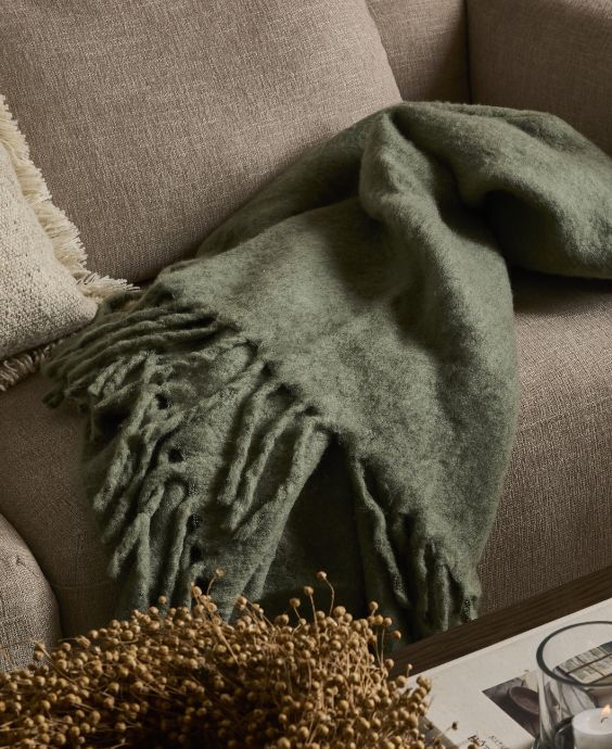 Grønt tæppe liggende på grå sofa