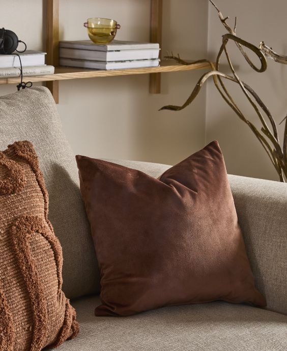 Udsnit af grålig sofa med røde puder