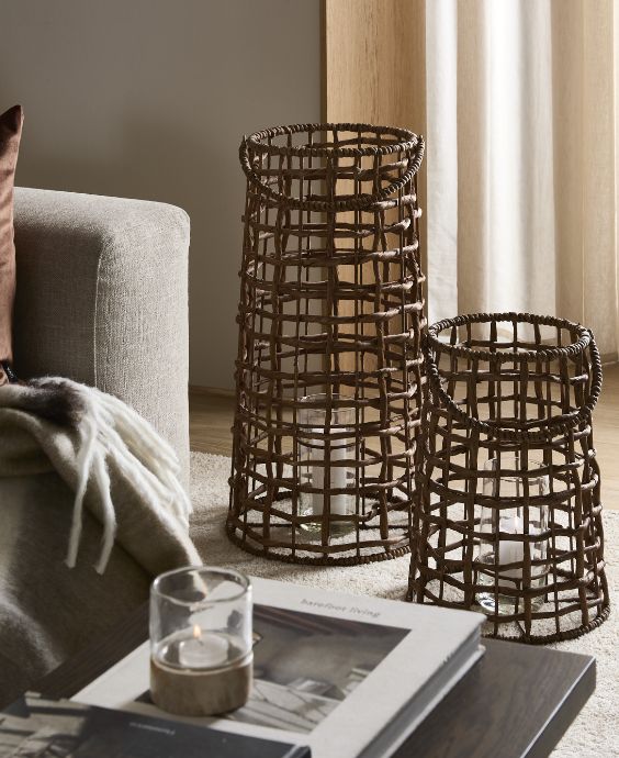 To flettede lanterne i forskellige højder stående på stuegulv