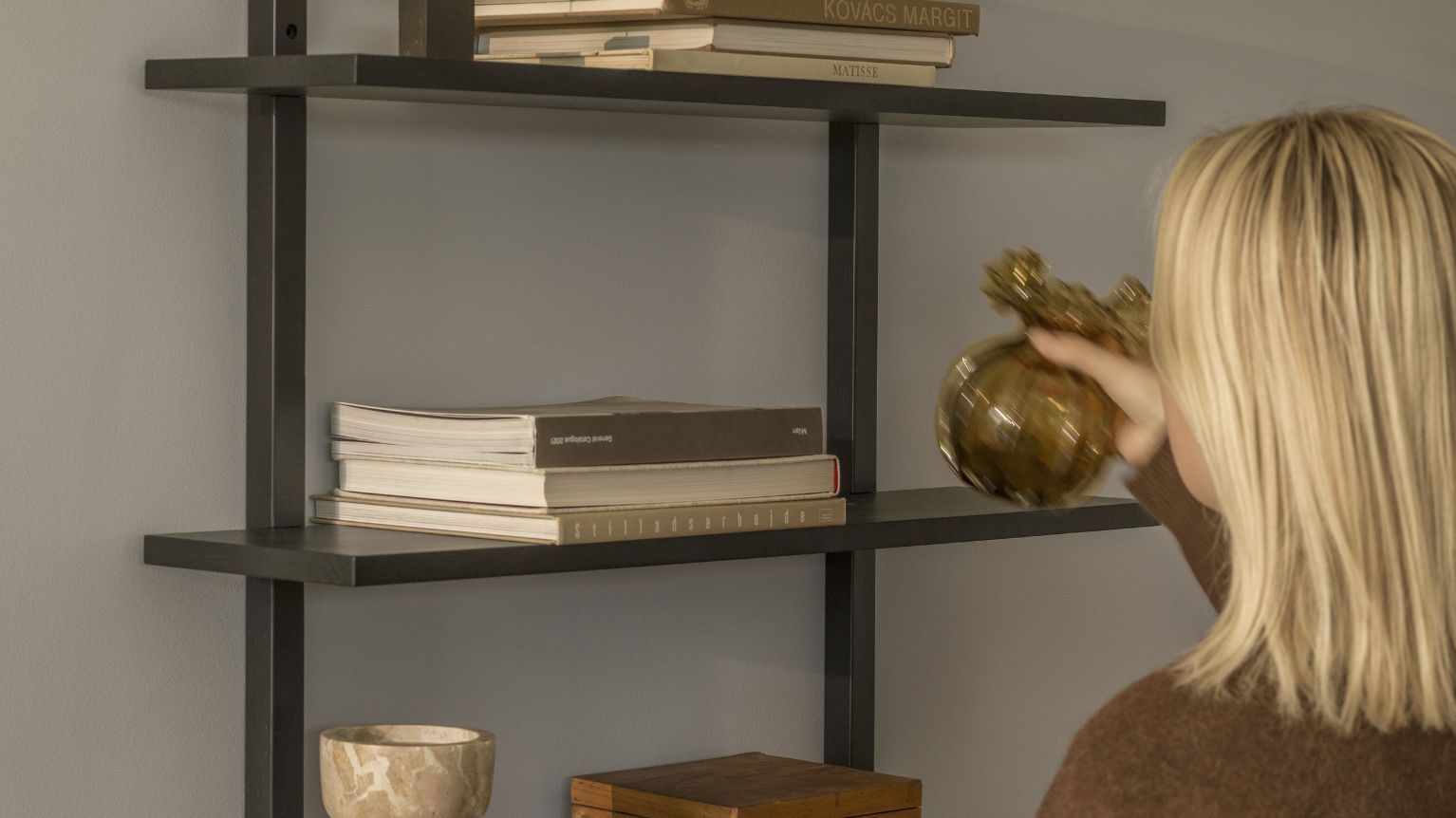 Kvinna framför svart hylla.