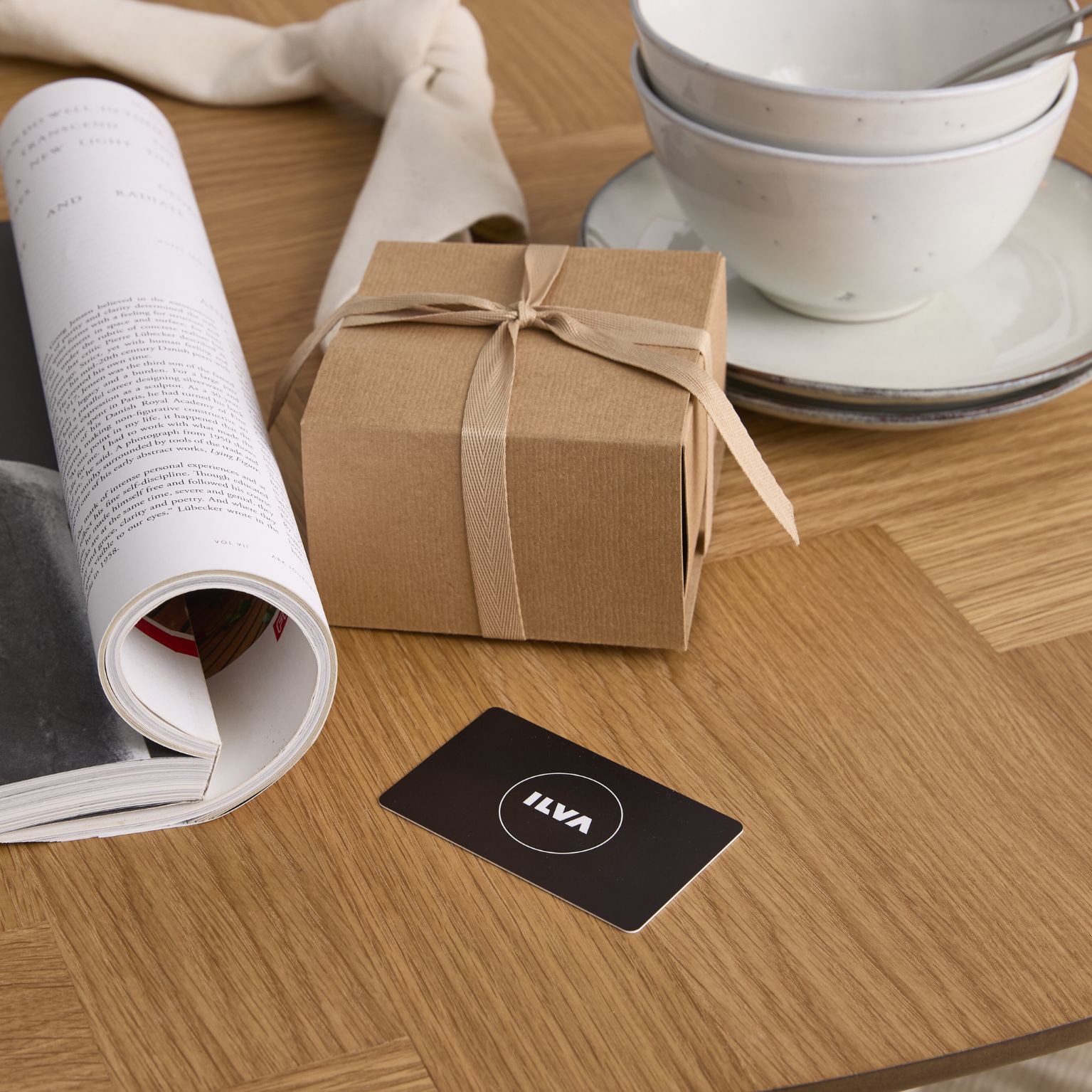 Svart presentkort från ILVA liggande på ett matbord i trä