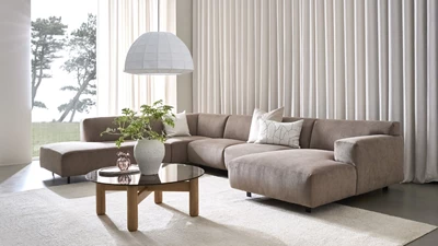 Design uden navn - 2025-10-14T105732.041.jpg Stor U-soffa med schäslong i grå nyans placerad framför ett stort fönsterparti.