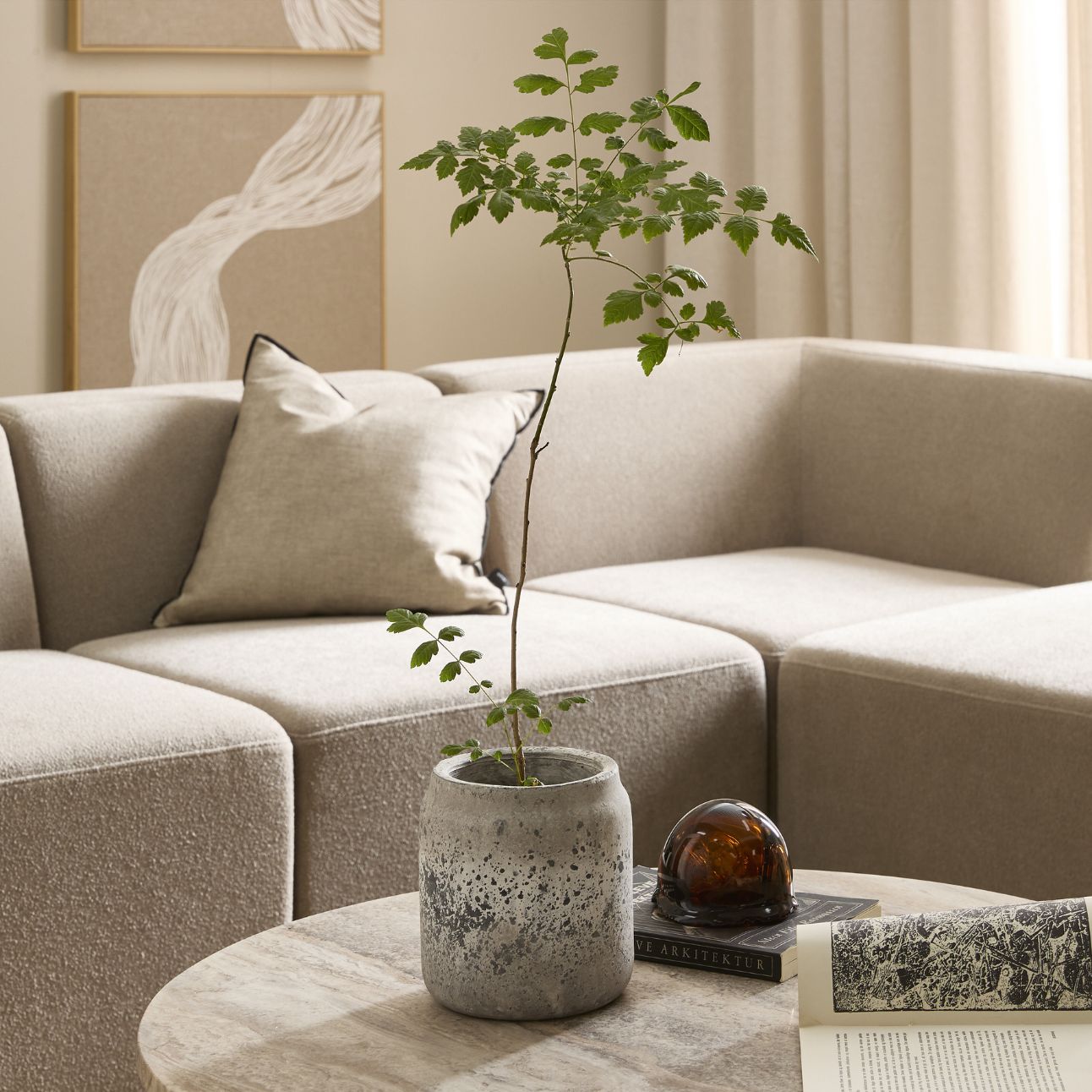 Hörnsoffa i grått med en kudde i matchande färg liggande i.