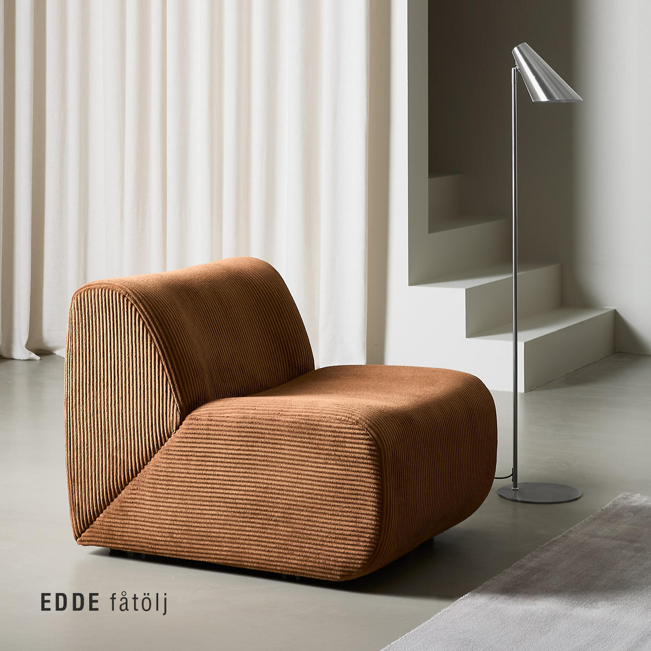 Röd fåtölj med organiska former på betongolv.