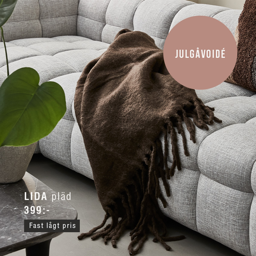 Brun pläd liggande på grå soffa.