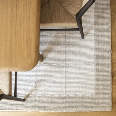 Ljus matta med rutor under soffbord i trä