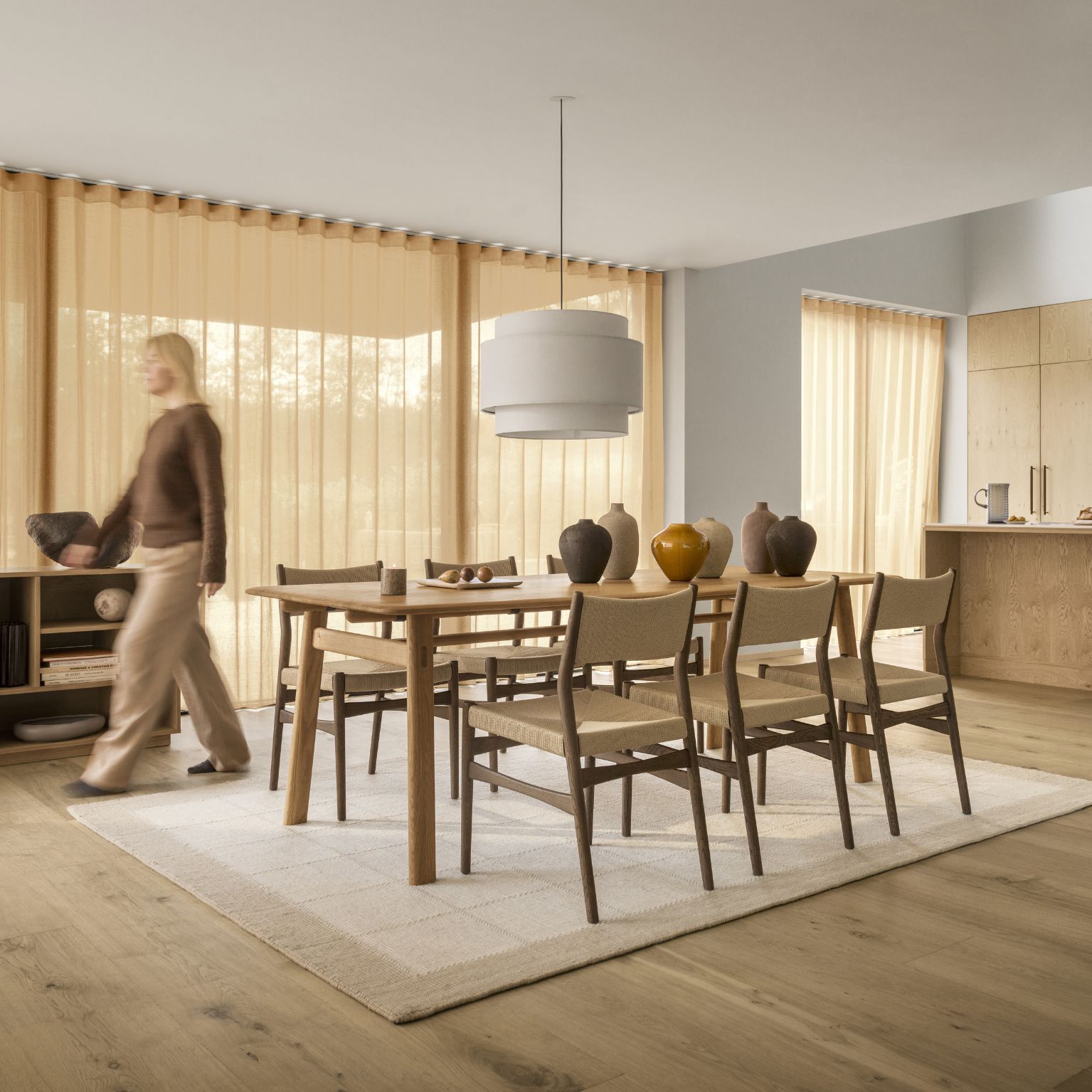 Matrum med matbord och stolar i trä. Under dem ligger en stor matta.