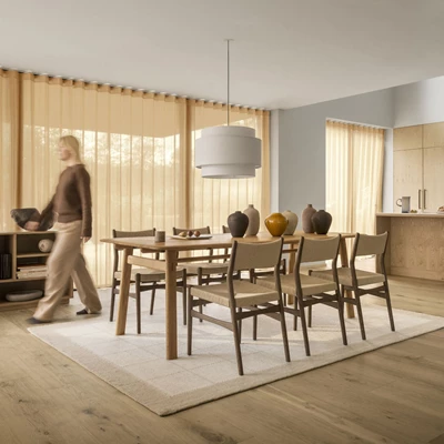 Matrum med matbord och stolar i trä. Under dem ligger en stor matta.