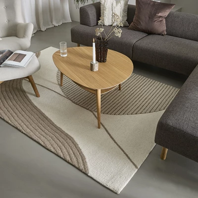 Matta med mönster i ljusa och bruna nyanser, placerad under soffbord i trä