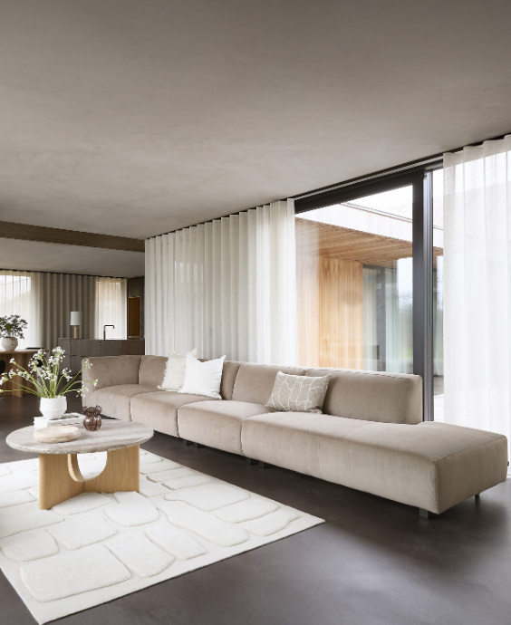 Vardagsrum med en soffa med open end i en grå nyans. På bilden finns en text med budskapet: Flexibel mys