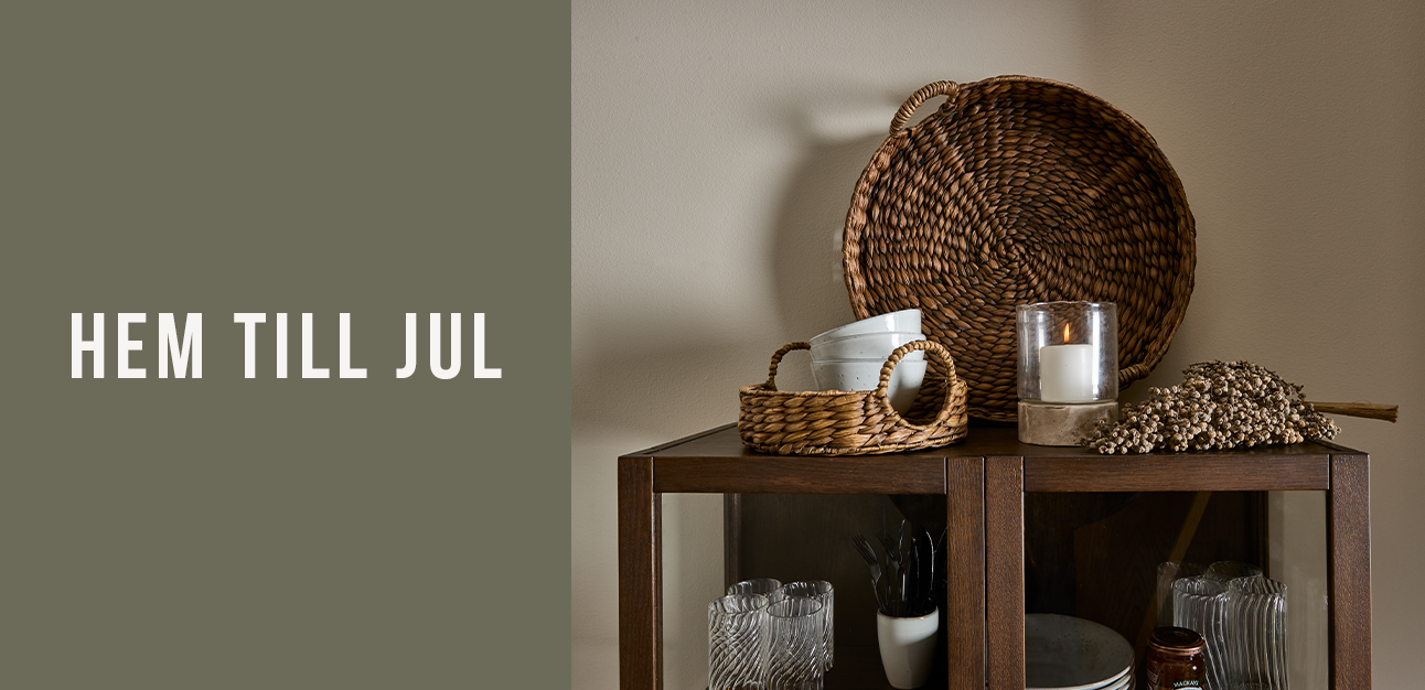 Inredningsdetaljer ovanpå ett vitrinskåp med en text som lyder ”hem till jul”