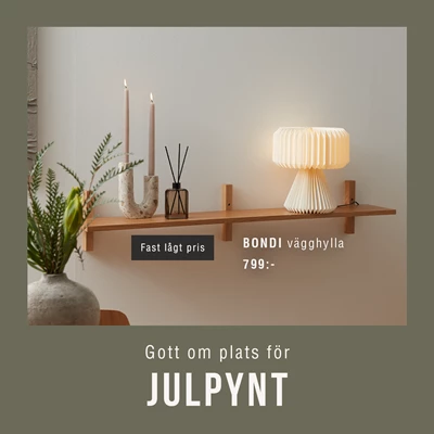 Hylla i trä med en papperslampa, en ljusstake och en doftdiffuser stående på.