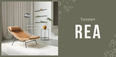 Beige loungestol FJELL i modernt vardagsrum med rea-skylt, neutrala färger och stilrena hyllor i bakgrunden.