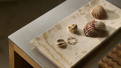 Alle Borde Og Stole (4) Bricka i brun marmor med smycken och snäckskal.